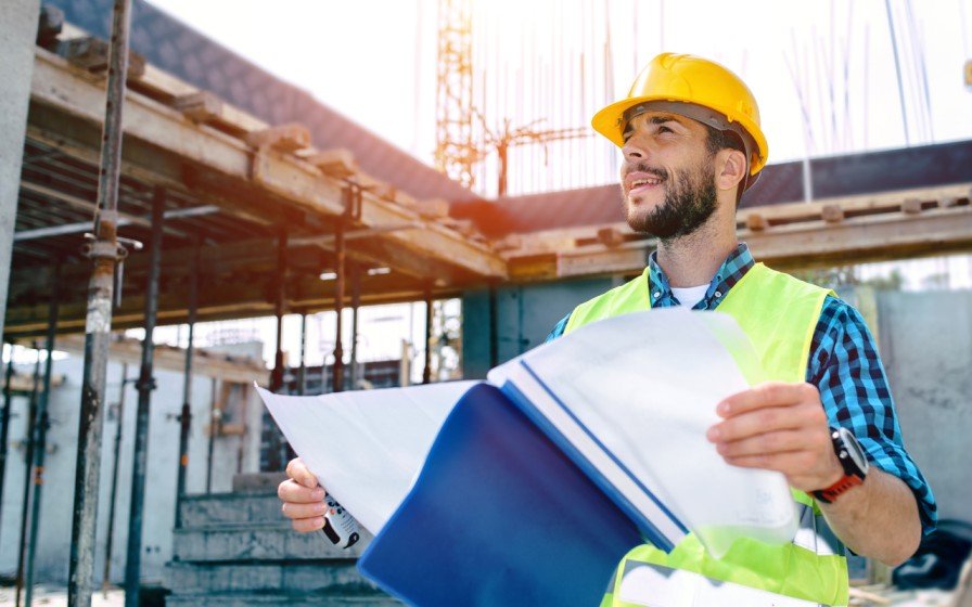 Construction worker holding a project file at a building site.
